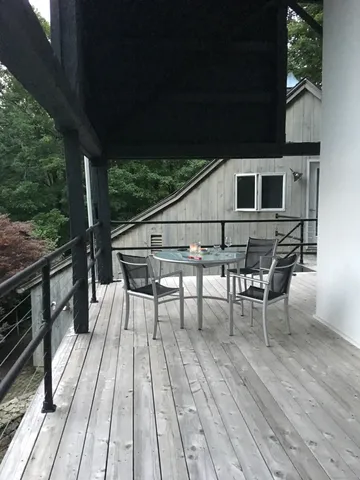 a roof deck with table and chairs with wooden floor