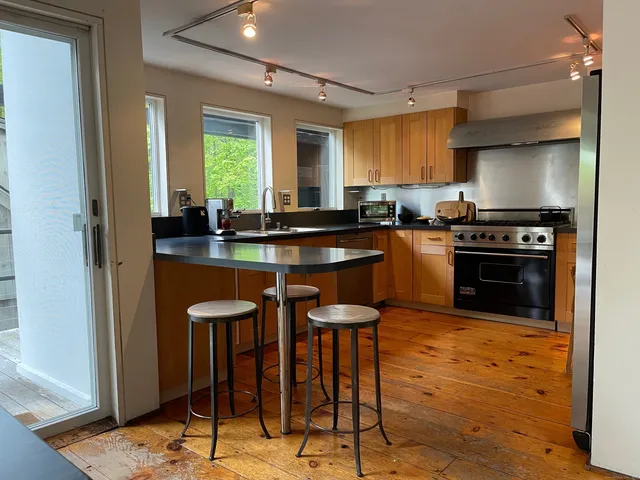 a kitchen with stainless steel appliances granite countertop table chairs sink and cabinets