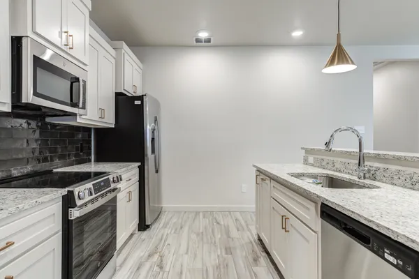 a kitchen with stainless steel appliances granite countertop a sink a stove and a refrigerator