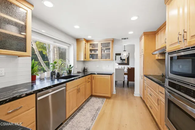 a kitchen with stainless steel appliances granite countertop a stove a sink and a microwave