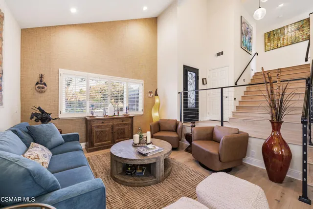 a living room with furniture kitchen view and a chandelier