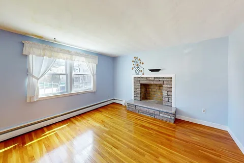 a view of an empty room with a window and fireplace