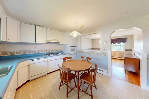 a kitchen with granite countertop a table chairs stove a sink and dishwasher