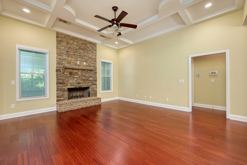 182 Oak Ridge Drive Waverly Hall, GA 31831 - Photo 24 of 52 an empty room with wooden floor a ceiling fan a fireplace and windows
