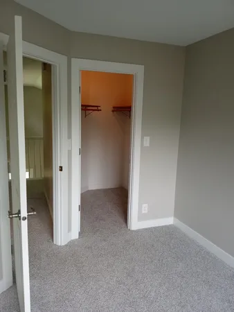 a view of an empty room with closet and a window
