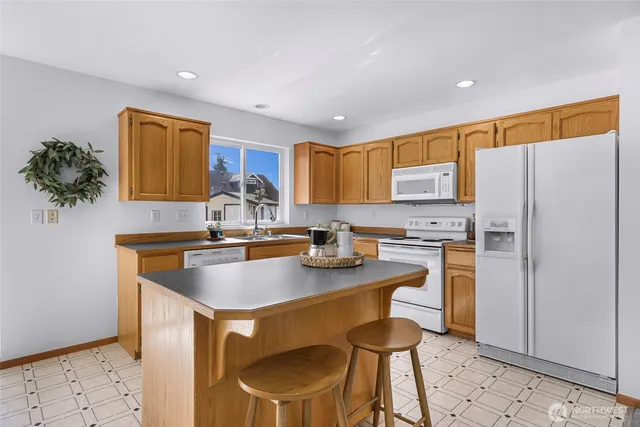 a kitchen with stainless steel appliances granite countertop a sink a stove a refrigerator cabinets and chairs