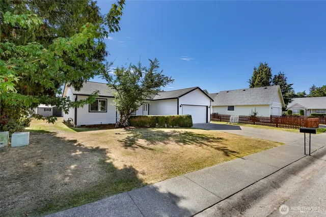 a view of a house with snow on the road and covered with tall trees