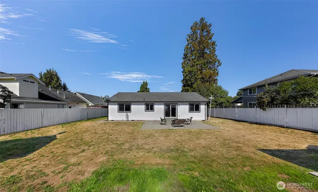 a backyard of a house with table and chairs under an umbrella