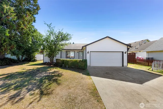 a view of a house with a yard and large tree