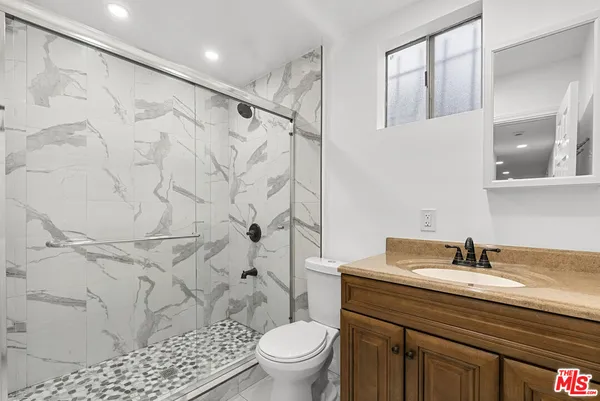 a bathroom with a granite countertop sink a toilet and shower