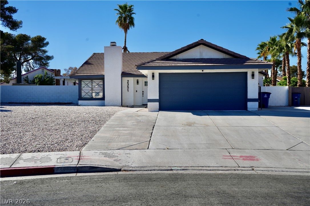 View of front facade with a garage, driveway, a tiled roof, and stucco siding