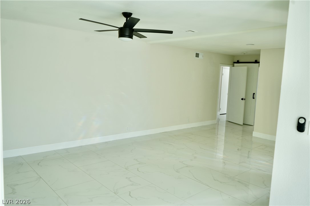 2351 Valleywood Road Henderson, NV 89014 - Photo 20 of 43 Unfurnished room with a barn door, light marble finish flooring, and a ceiling fan