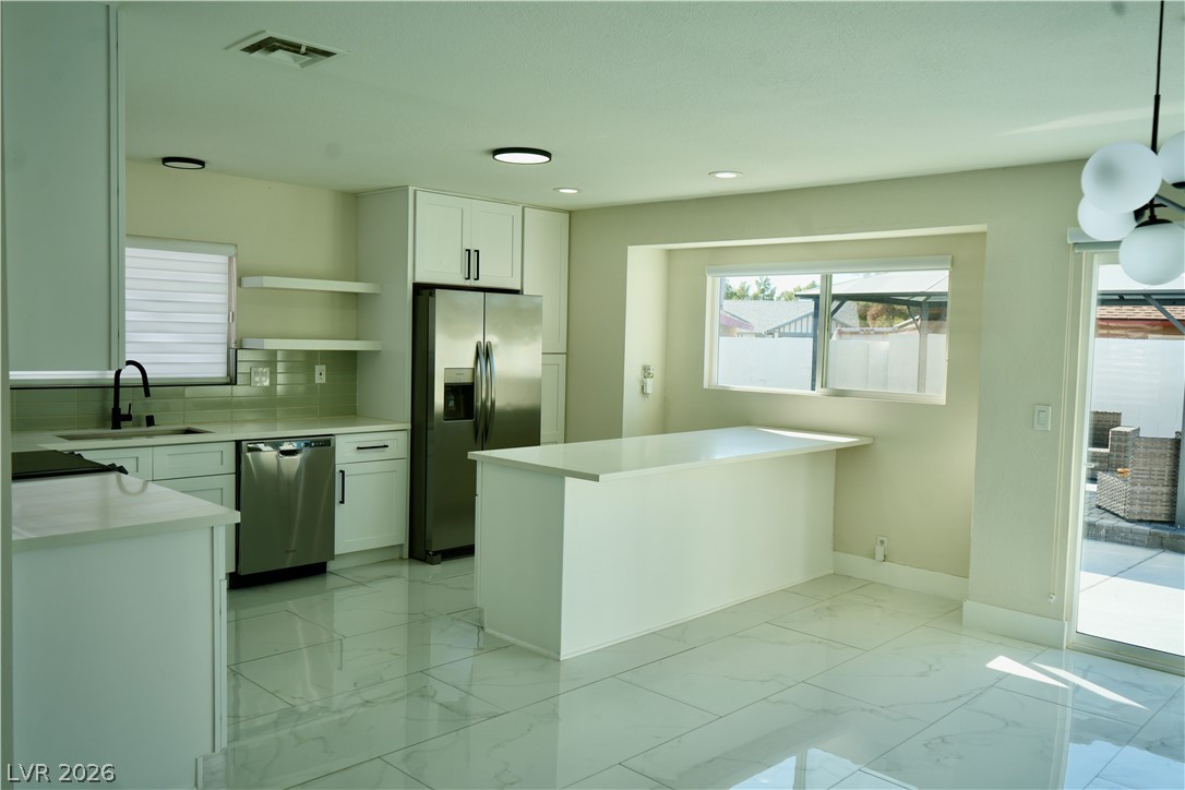 2351 Valleywood Road Henderson, NV 89014 - Photo 9 of 43 Kitchen with white cabinets, stainless steel appliances, light marble finish floors, open shelves, and a peninsula
