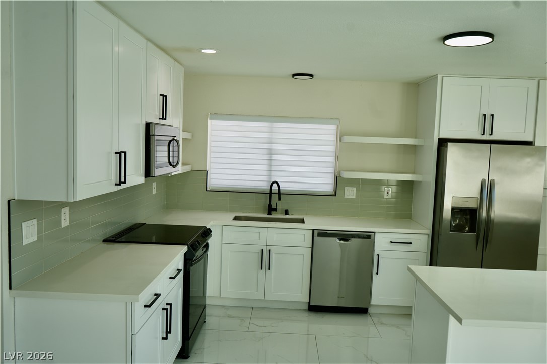 2351 Valleywood Road Henderson, NV 89014 - Photo 10 of 43 Kitchen with stainless steel appliances, light marble finish floors, white cabinetry, open shelves, and backsplash