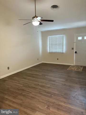 an empty room with wooden floor chandelier fan and windows