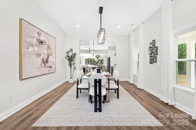 a dining room with wooden floor and large windows