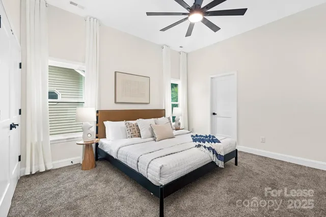 a bedroom with a bed lamp and a ceiling fan