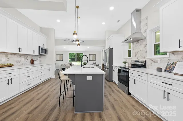 a kitchen with stainless steel appliances kitchen island hardwood floor sink stove dining table and chairs