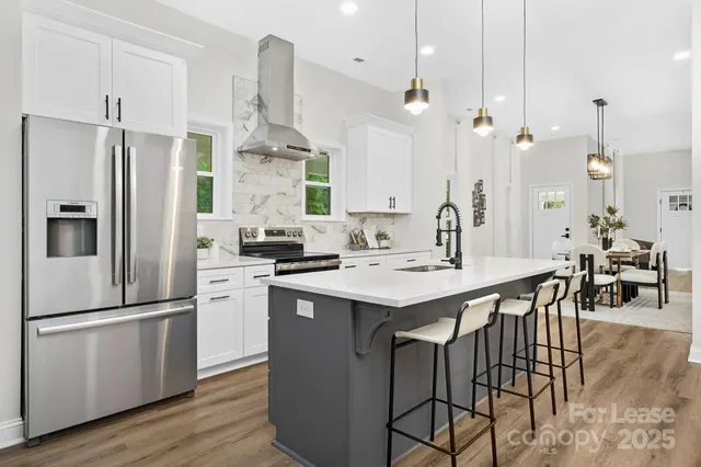 a kitchen with stainless steel appliances granite countertop a sink a stove a refrigerator and island with wooden floor