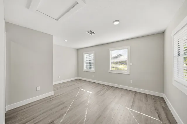 an empty room with wooden floor and windows