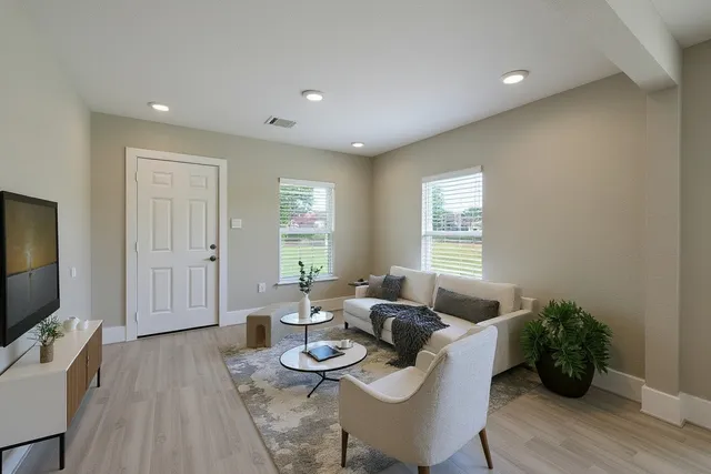a living room with furniture a flat screen tv and wooden floor