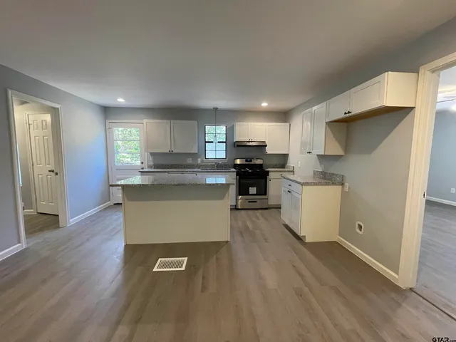 a large kitchen with stainless steel appliances granite countertop a stove a sink dishwasher and a refrigerator