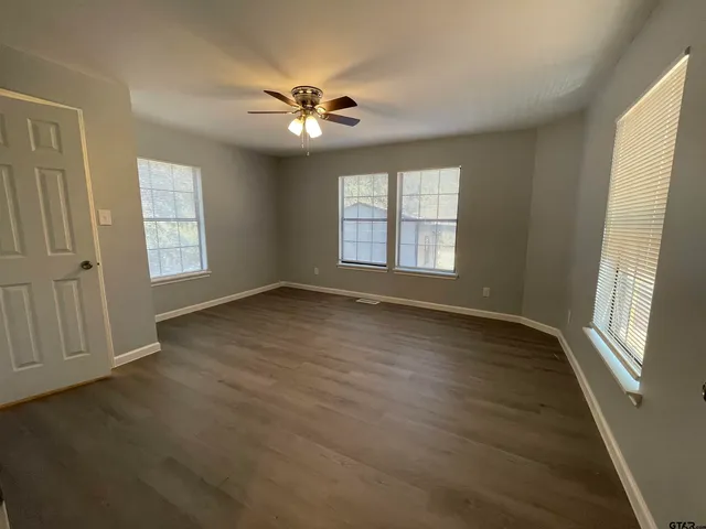 a view of an empty room with wooden floor and a window