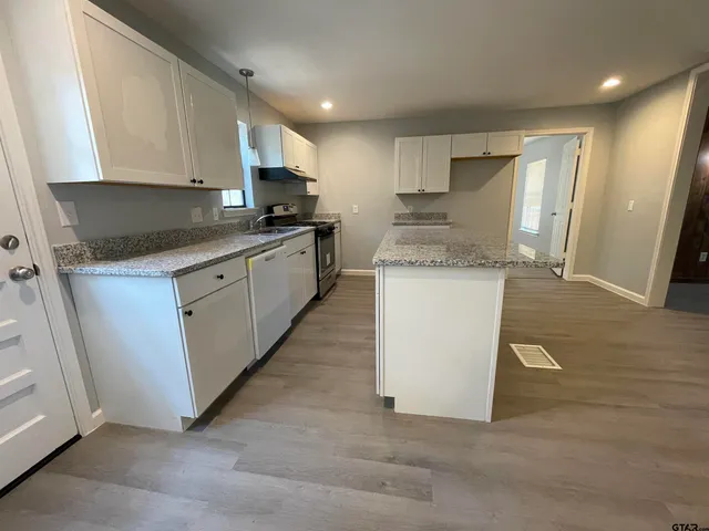 a kitchen with stainless steel appliances granite countertop a stove top oven a sink and a refrigerator