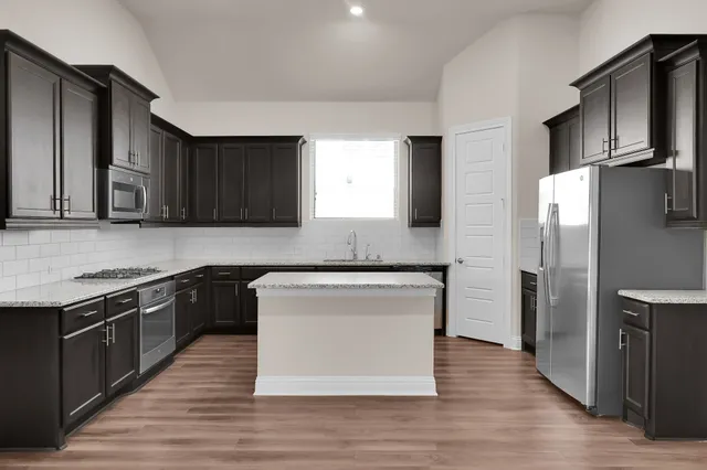 a kitchen with stainless steel appliances granite countertop a stove a refrigerator and a microwave