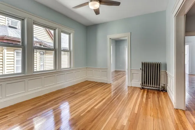 a view of empty room with wooden floor and fan