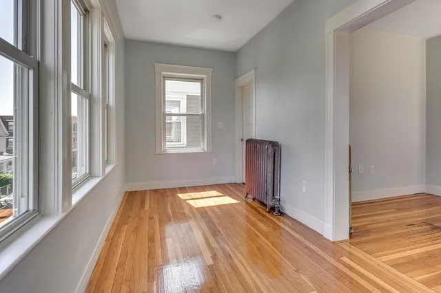 a view of a room with wooden floor a fireplace and windows