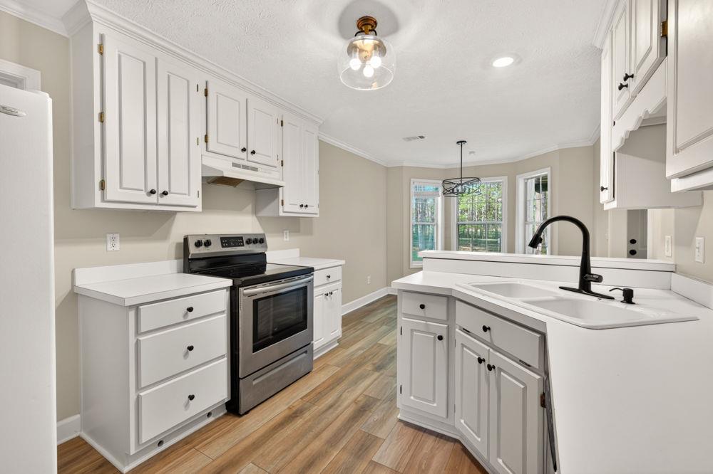 4035 Lakeside Boulevard Monroe, GA 30655 - Photo 5 of 43 a kitchen with stainless steel appliances a sink dishwasher a stove and white cabinets with wooden floor