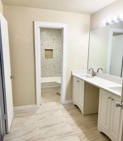 a bathroom with a double vanity sink a mirror and a bathtub