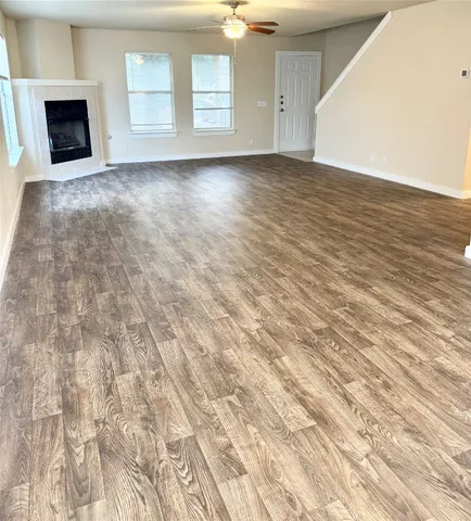 an empty room with wooden floor fireplace and windows