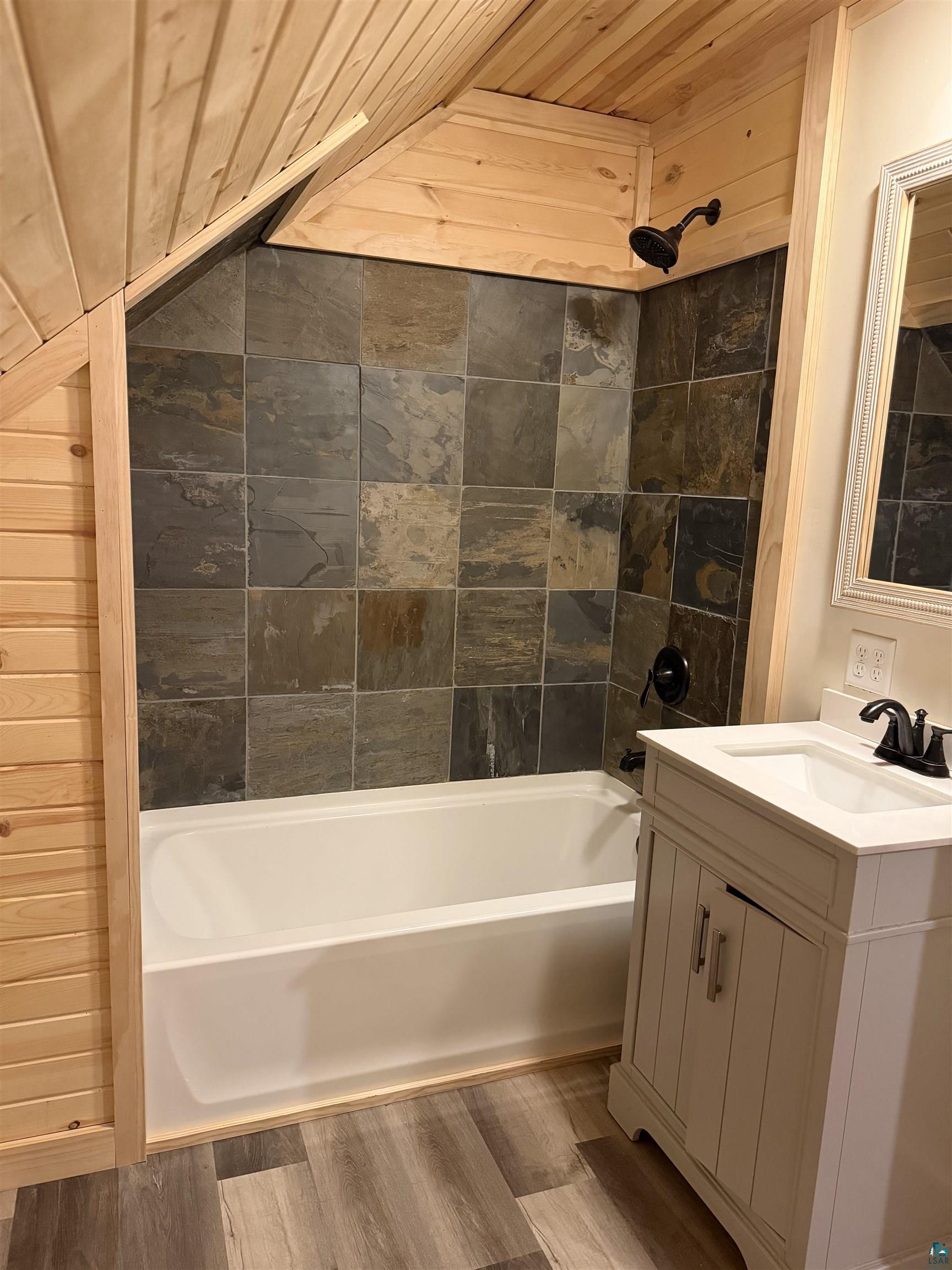 5274 Marble Lake Road Two Harbors, MN 55616 - Photo 44 of 79 Bathroom featuring a full-size tub with slate-style tile surround and a matte black showerhead