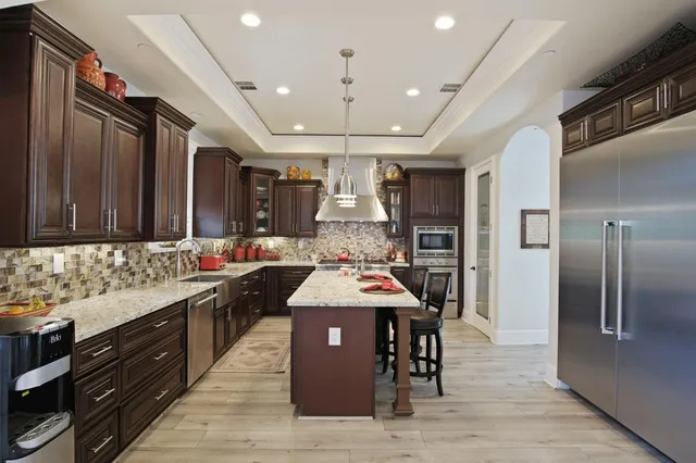 a large kitchen with stainless steel appliances kitchen island granite countertop a stove refrigerator and cabinets