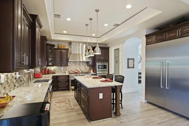 a kitchen with stainless steel appliances granite countertop a sink a stove and a refrigerator