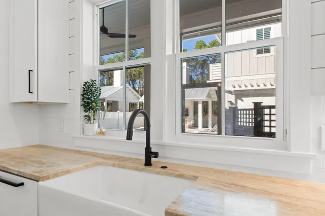 a large white kitchen with a lot of counter space and wooden floor