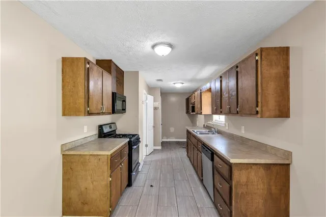 a kitchen with stainless steel appliances granite countertop a sink a stove and a wooden floors