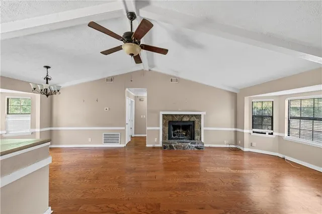 wooden floor in an empty room with a fireplace and a window