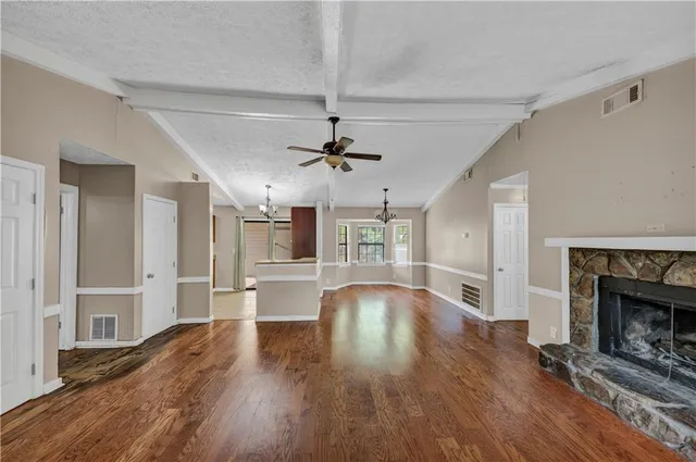 a view of an empty room with wooden floor fireplace and a window