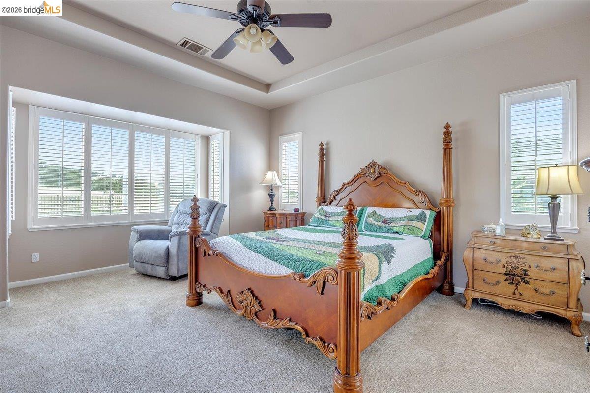 158 Rock Ridge Lane Copperopolis, CA 95228 - Photo 30 of 72 Primary Bedroom with bay window featuring white plantation shutters, ceiling fan with integrated lighting, and tray ceiling detail