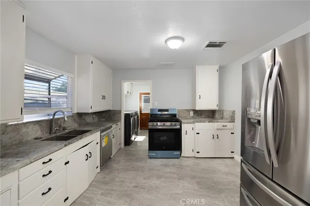 a large kitchen with cabinets a sink and stainless steel appliances