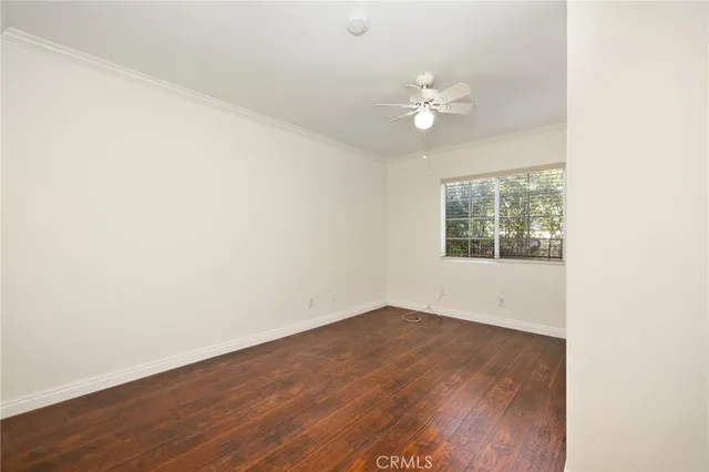 an empty room with wooden floor chandelier fan and windows