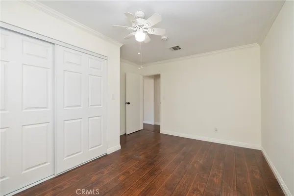 an empty room with wooden floor and a ceiling fan