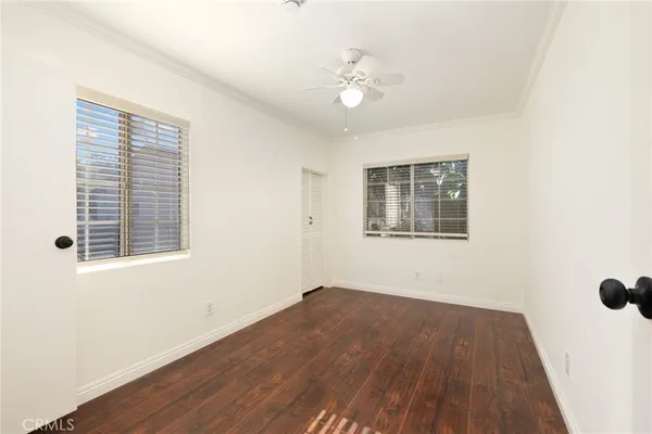 a view of empty room with wooden floor and fan