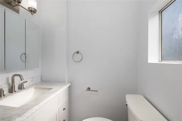 a bathroom with a granite countertop sink a toilet and mirror