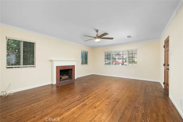 a view of a livingroom with a fireplace a ceiling fan and windows