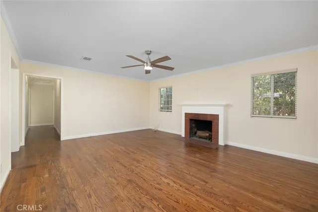 a view of a livingroom with a fireplace a ceiling fan and wooden floor