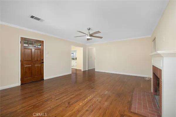 a view of an empty room with a window and wooden floor